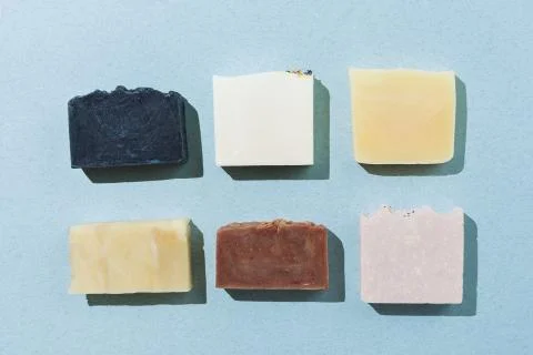 Flatlay of various natural hand-made soaps on blue, selective focus Stock Photos