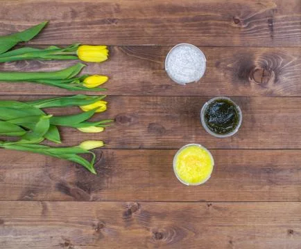 Flatlay view spa cosmetics products scrub for face and body on brown wood bac Stock Photos