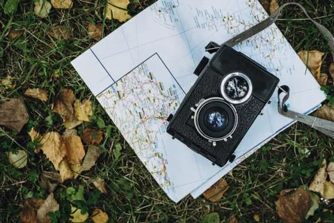 Flatlay of vintage two-lens camera lying on map on the grass Stock Photos