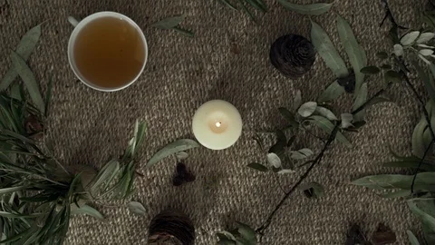 Flatlay with wicker mat, dry plants, a burning candle and a cup of herbal tea Stock Footage 124861948