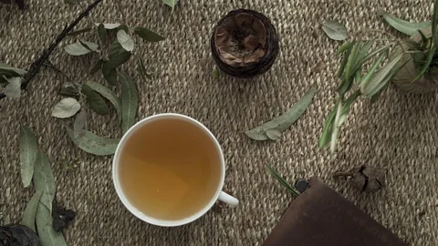 Flatlay with wicker mat, dry plants, a notebook and a cup of herbal tea. Close Stock Footage 124862444