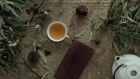 Flatlay with wicker mat, dry plants, a notebook, teapot and a cup of herbal tea Stockbeeldmateriaal 124862623