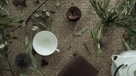 Flatlay with wicker mat, dry plants, a notebook, teapot and a cup of herbal tea Stock Footage 124862992