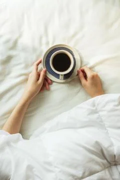 Flatlay of woman's hands covered by blanket holding cup of black coffee on a  Stock Photos