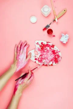 Flatlay with woman's hands covered in paint holding brush and palette and oth Stock Photos