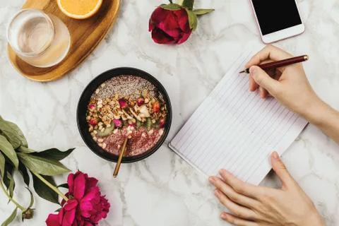 Flatlay of woman's hands with notebook and smartphone, vegan smoothie bowl wi Stock Photos