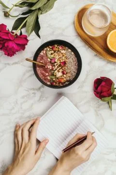 Flatlay of woman's hands with notebook and smartphone, vegan smoothie bowl wi Stock Photos