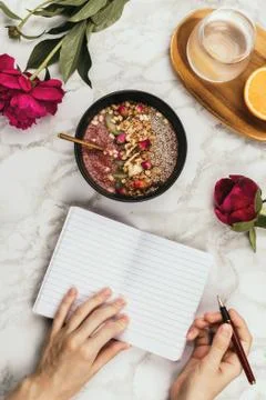 Flatlay of woman's hands with notebook and smartphone, vegan smoothie bowl wi Stock Photos