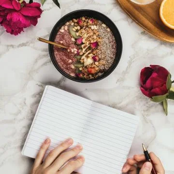 Flatlay of woman's hands with notebook and smartphone, vegan smoothie bowl wi Stock Photos