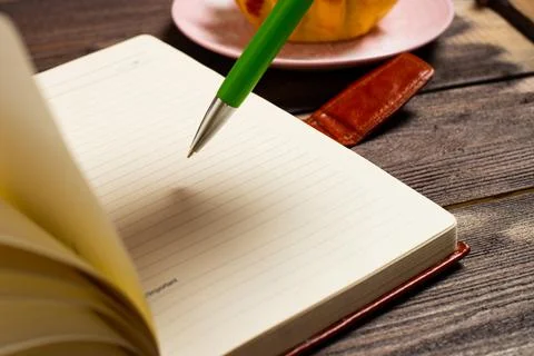 Flatley layout. An open notebook, a green pen on an old dark wood table. Stock Photos