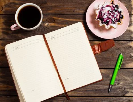 Flatley layout. An open notebook, a green pen, black coffee in a cup and a ca Stock Photos