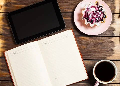 Flatley layout. Open notebook, tablet gadget, black coffee in a cup and a cak Stock Photos