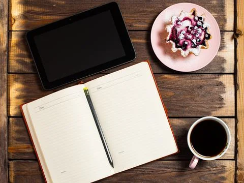 Flatley layout. Open notebook, tablet gadget, black coffee in a cup and a cak Stock Photos