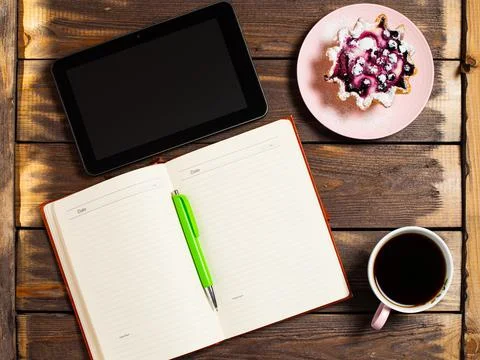 Flatley layout. Open notebook, tablet gadget, black coffee in a cup and a cak Stock Photos
