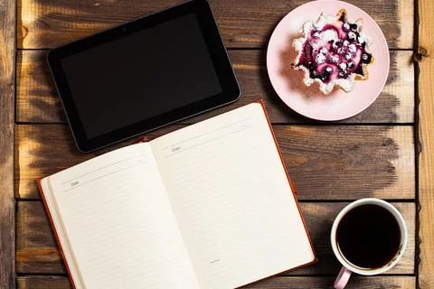 Flatley layout. Open notebook, tablet gadget, black coffee in a cup and a cak Stock Photos