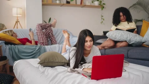 Flatmate girls studying and watching the cell phone relaxed on the bed with Stock Footage 307020646