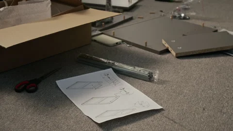 Flatpack Drawer Assembly Instruction Leaflet and Components on Floor at Home Stock Footage 330508656