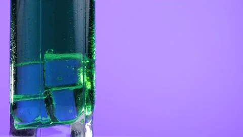 Flavored green lemonade with ice cubes in a glass rotate on a violet background. Stock Footage 130462754