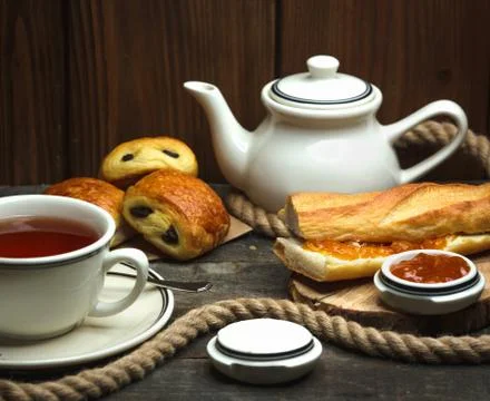 Flavored tea and a loaf of bread buttered with jam Stock Photos