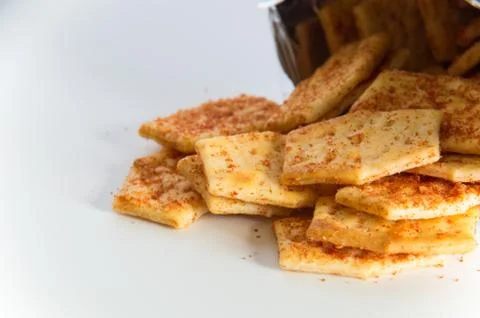 Flavoured biscuits spilling out of the packaging onto a white bench Stock Photos