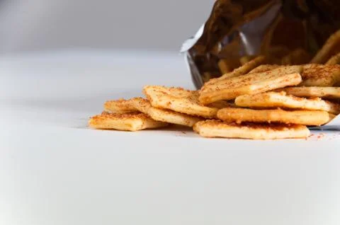 Flavoured biscuits spilling out of the packaging onto a white bench Stock Photos