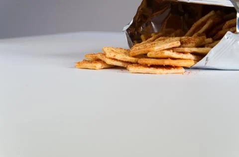 Flavoured biscuits spilling out of the packaging onto a white bench Stock Photos