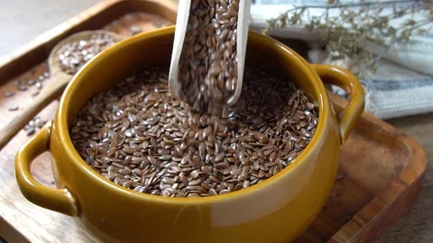 Flax seed poured in slow motion into rustic bowl. Video stock 124287922