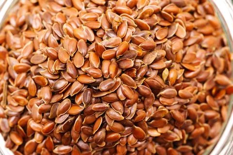 Flax seeds in a clear container on a flat surface in a bright area 库存照片