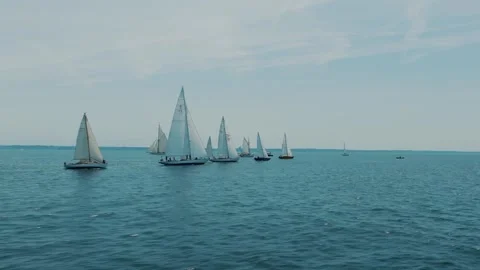 Fleet of classic sailing yachts racing together across calm blue sea during Stock Footage 345293055