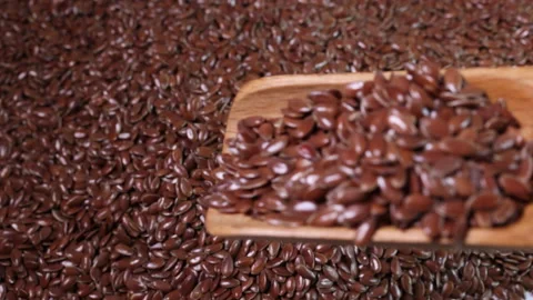 Flex seed flaxseed drop pour from wooden spoon scoop  Stock Footage 157899664