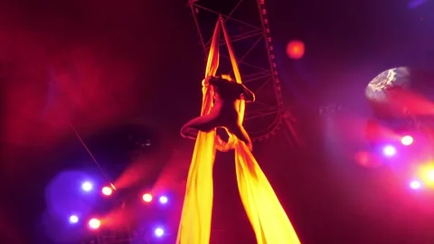 A flexible aerial gymnast performs tricks on fabric under the dome of the circus Stock Footage 310656545