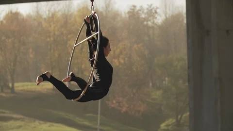 Flexible brunette doing some acrobatic elements on aerial hoop outdoors Stock Footage 101851383