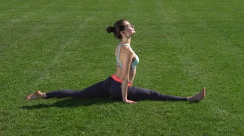 Flexible girl doing gymnastic exercises on the grass Stock Footage