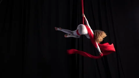Flexible girl performs on stage on red aerial silks. Professional circus artist Stock Footage 197900819