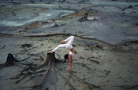 Flexible gymnast girl in a beautiful pose on a background of apocalyptic land Stock Photos