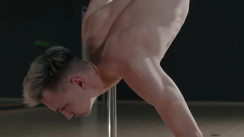 Flexible Man Doing Pole Dance Elements from Floor in Studio Stock Footage 276345737