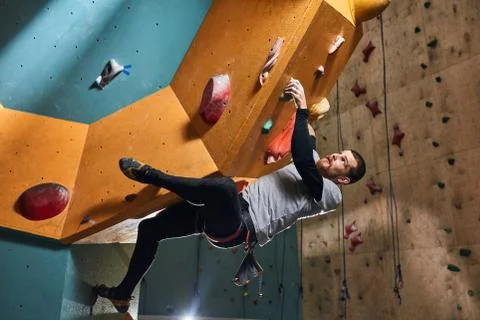 Flexible physically challenged boulderer overhanging at large rock wall Stock Photos