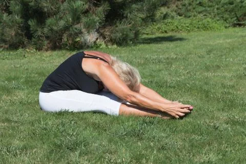 Flexible senior blonde woman is exercising outdoors Stock Photos