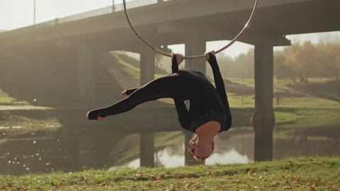 Flexible woman doing acrobatic elements on aerial hoop. Brunette hanging in ring Stock Footage 99220850