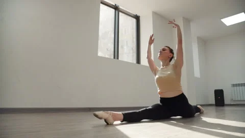 Flexible young ballerina doing longitudinal split sitting at dance hall 库存影片 201596993