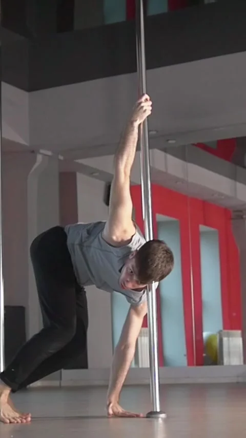 Flexible young man performing pole dance elements on a pole Stock Footage 346813475