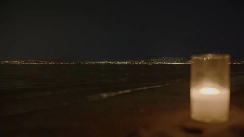 Flickering candle with distant city lights on beach Stock-Footage 252735003