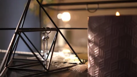 Flickering candle illuminating a pair of silver earrings Stock Footage 328006615