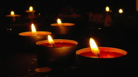 Flickering red tea light candles burn in a dark atmospheric scene, warm Stock Footage 344880761