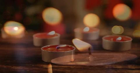 Flickering tealight candle cluster casting warm glow on wood table, with molten Stock Photos