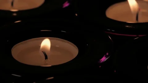 Flickering tealight candle flame burning wick close up in purple glass holder Stock Footage 73954169