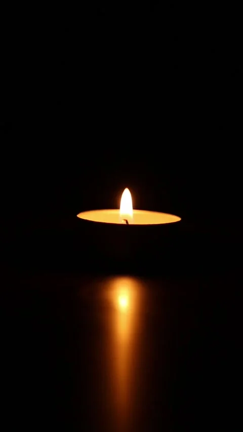 Flickering tealight candle with warm reflection on black background Stock-Footage 340272331