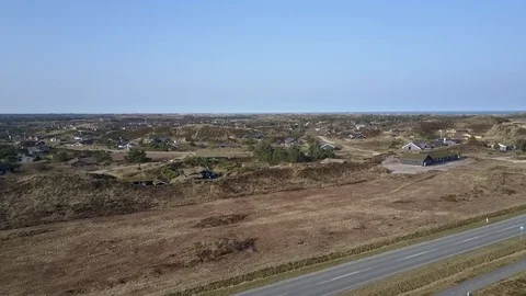 Flight above grass covered dunes and holiday houses at Henne Strand Stock Footage 87256466
