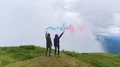 The flight above man and woman with smoke bombs on a mountain top 4k or 4k+ Resolution