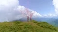 The flight above man and woman with smoke bombs on the mountain 4k or 4k+ Resolution